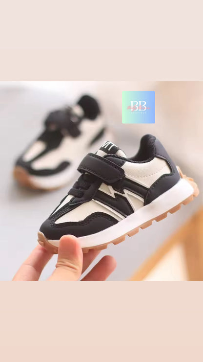 Black and white sneakers held by a hand on a light background