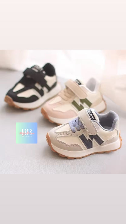 Three pairs of children's sneakers on a light background