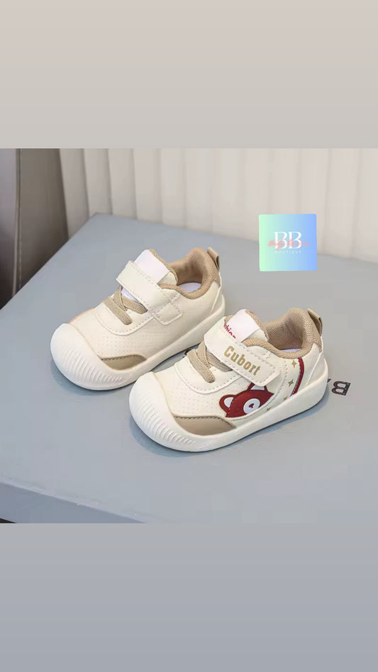 Pair of children's shoes with a bear design on a light gray surface.