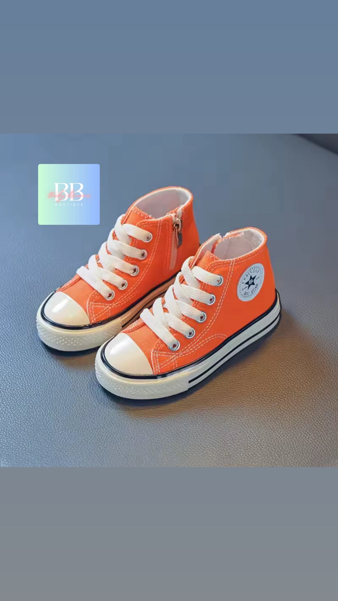 Pair of orange high-top sneakers with white laces on a blue surface