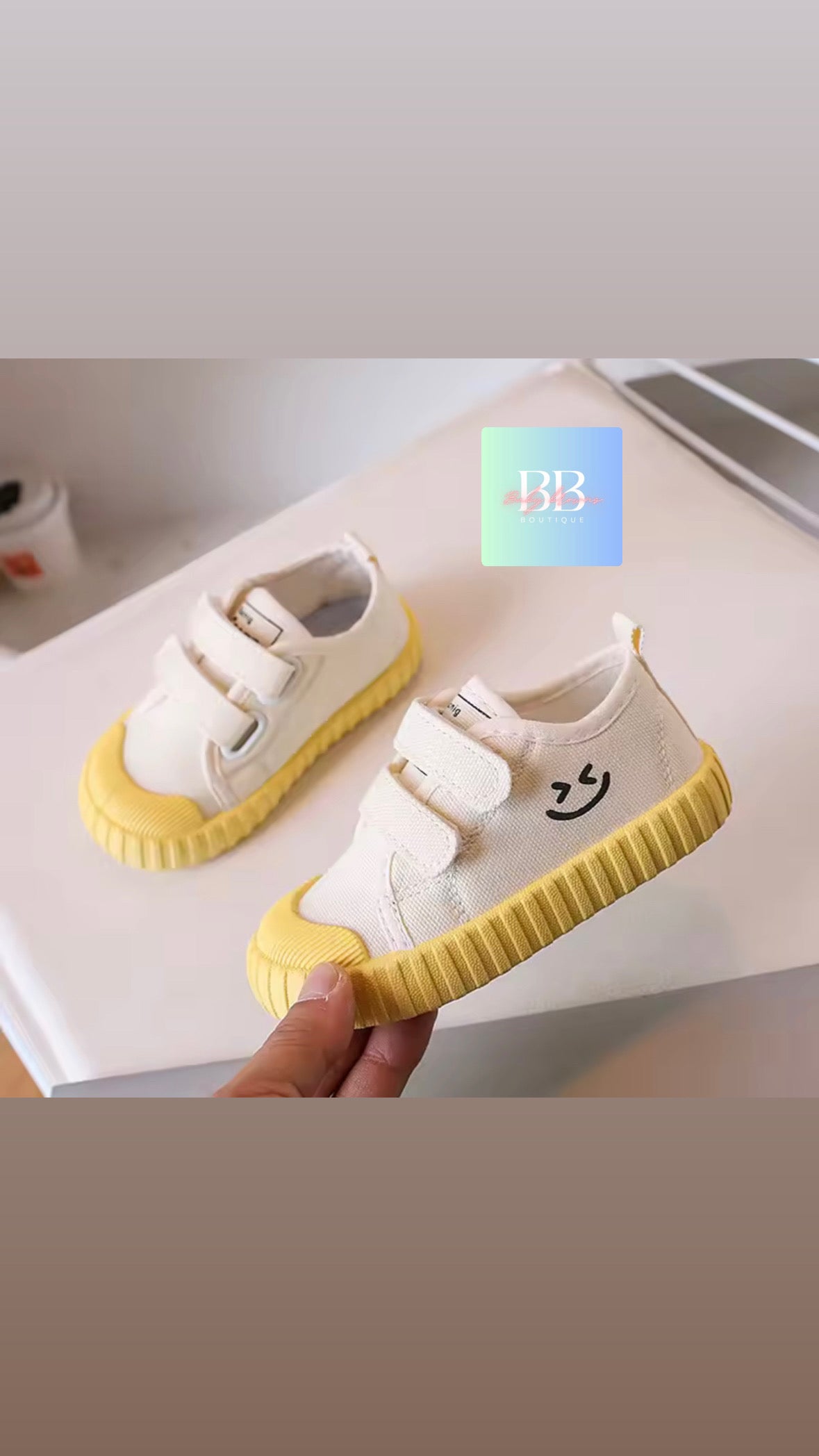 White and yellow children's shoes with a smiley face design on a white surface.