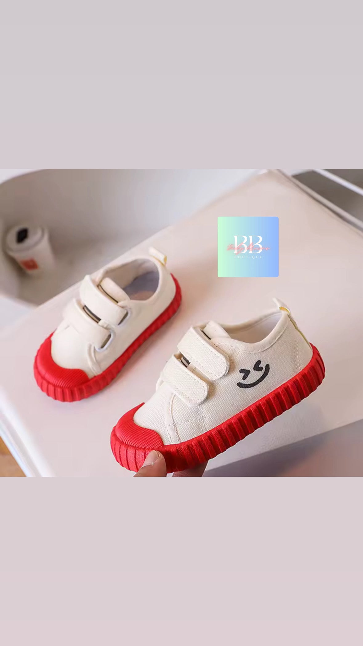 White children's shoes with red soles on a light background