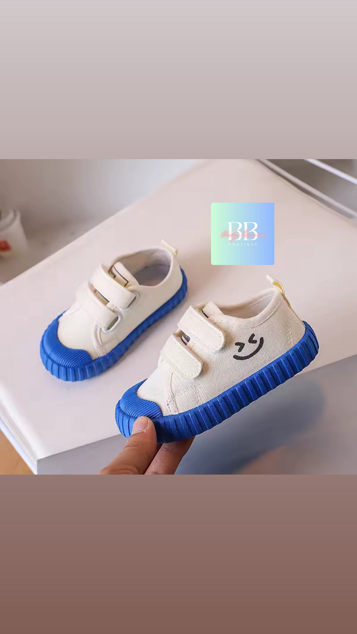 White shoes with blue soles held by a hand on a light background