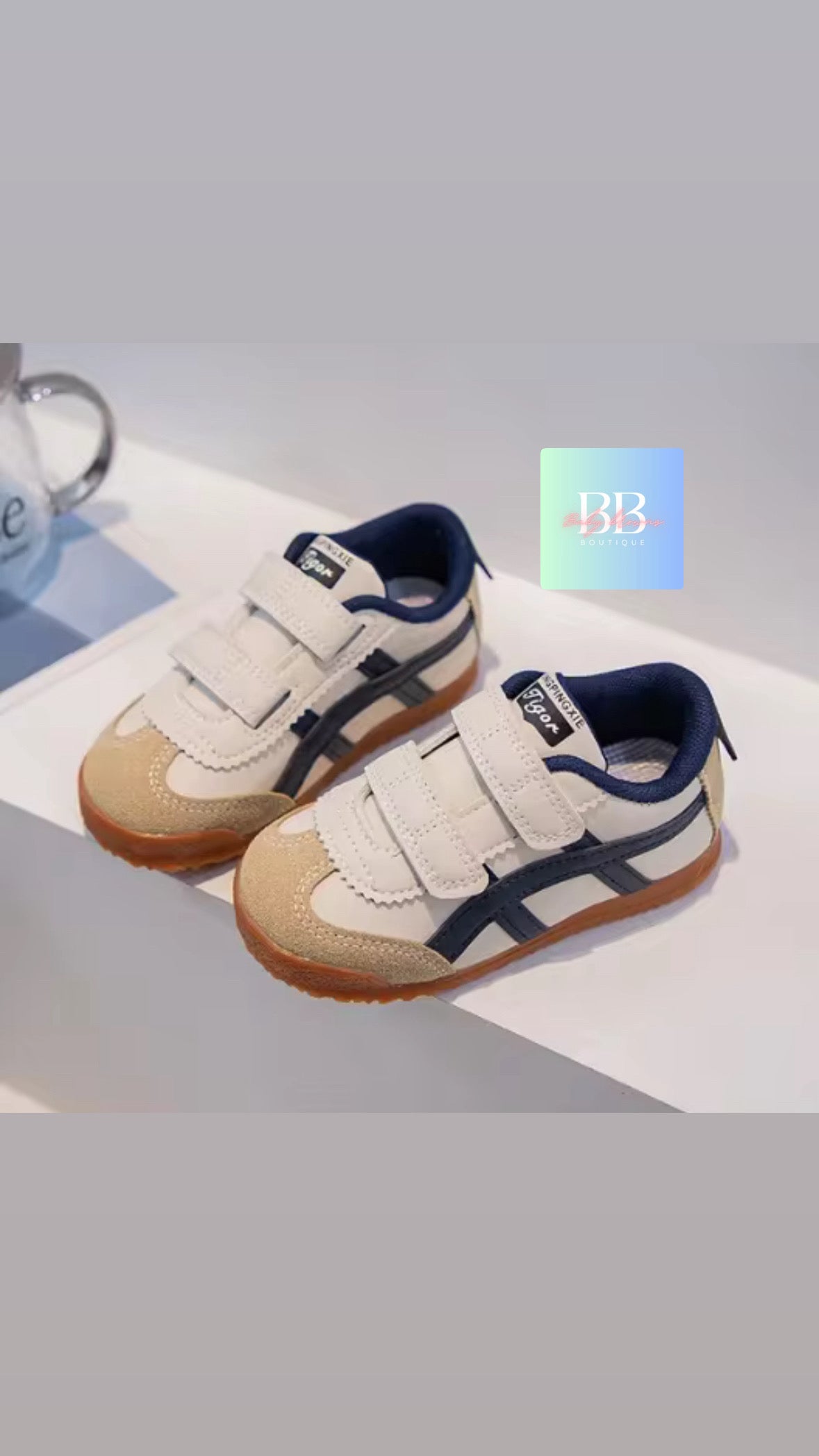 Pair of children's shoes with white and navy design on a light gray background