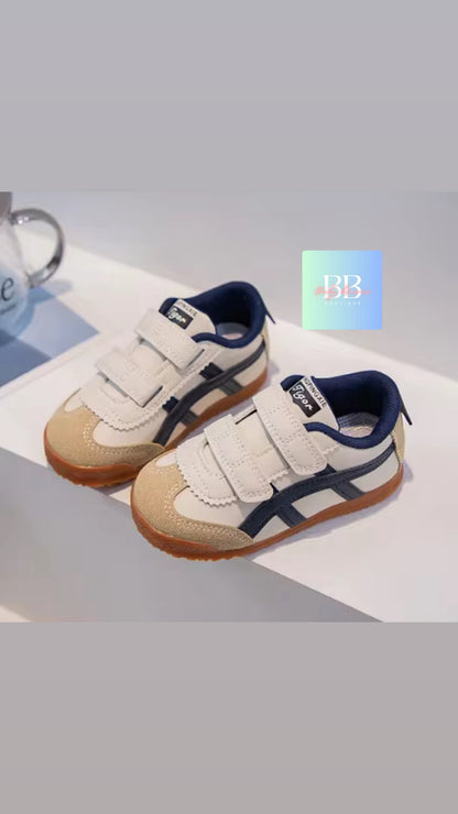 Pair of children's shoes with white and navy design on a light gray background