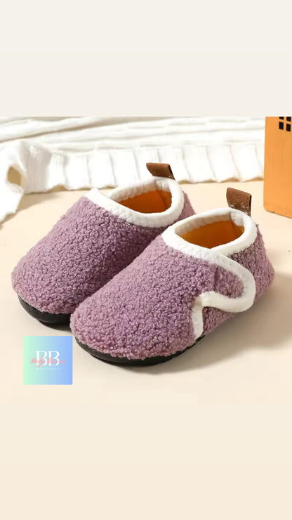Pair of purple slippers with white accents on a light background