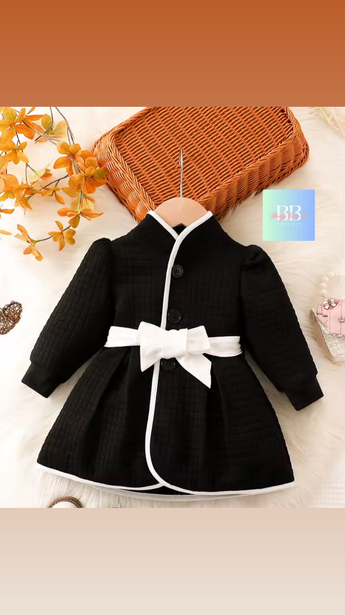 Black dress with a white belt on a hanger against a neutral background