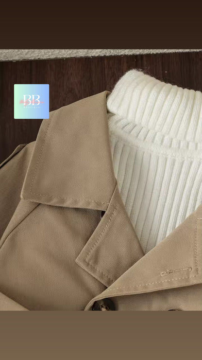 Close-up of a beige trench coat with a white textured pillow against a wooden background