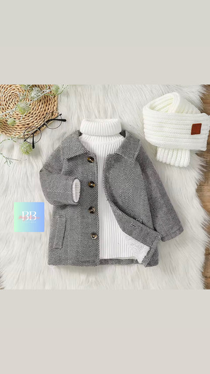 Gray coat with white turtleneck sweater and white beanie on a textured surface