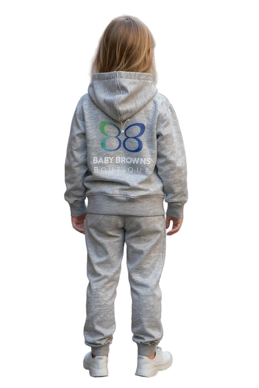 Child wearing a gray hoodie and pants with a visible brand logo on a city street.