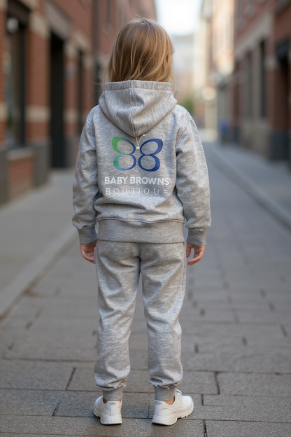 Child wearing a gray hoodie and pants with a visible brand logo on a city street.